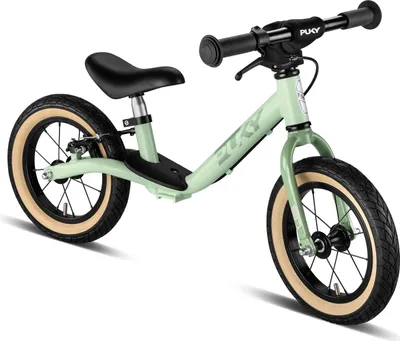 A light green Puky balance bike with black seat and handlebars, and tan tires, is shown against a white background.