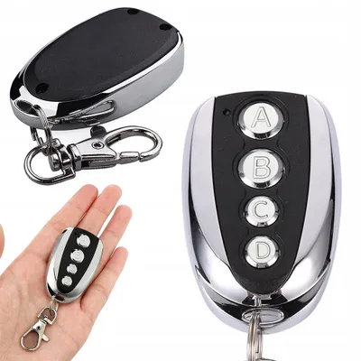 A hand holding a remote control, with other remote controls in the background.