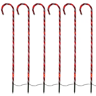 Six illuminated candy cane garden stakes arranged in a row against a white background.