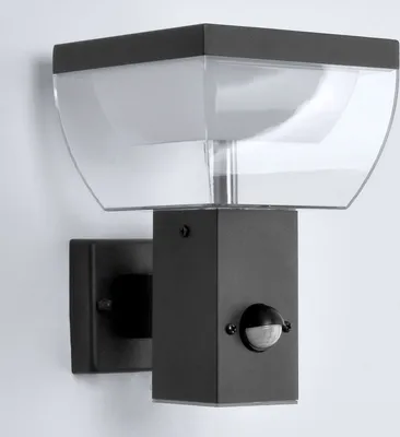 A black outdoor wall light with a clear plastic cover is mounted on a white wall.
