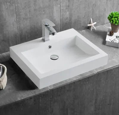 A white rectangular sink with a chrome faucet is shown on a gray tiled countertop.