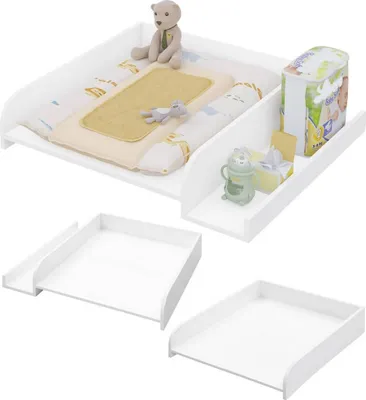 A white baby changing station with a teddy bear, baby bottle, and diaper pack on it. The changing station is shown from a slightly elevated angle, with a white background.