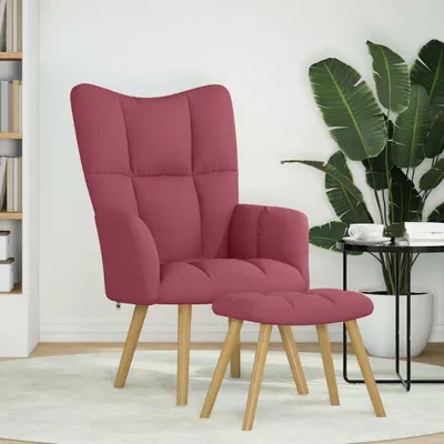 A pink armchair and ottoman are placed on a light-colored rug in a room with a bookshelf and a large potted plant.