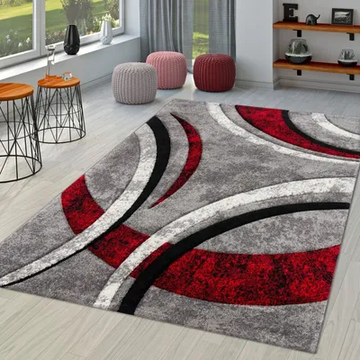 A modern living room with a geometric rug, side tables, and poufs.