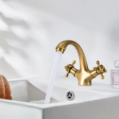 A brass faucet with water running into a white sink.