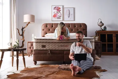 A couple relaxing in a bedroom with a large bed.