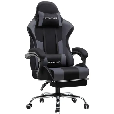 A gaming chair with a footrest, headrest, and lumbar pillow.