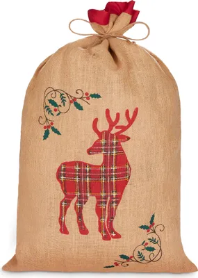 A burlap Christmas sack with a red plaid reindeer design and holly accents, tied at the top with twine and a red fabric ribbon.