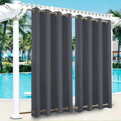 Outdoor curtains hanging on a pergola next to a swimming pool with palm trees in the background.