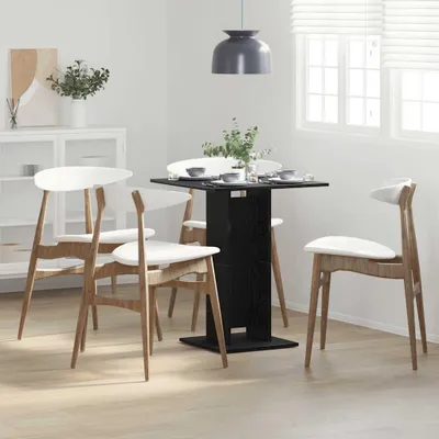 A dining set with a black table and four white chairs in a bright, modern room.