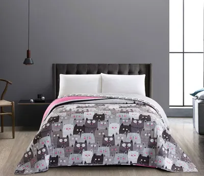 A bed with a blanket featuring a cat pattern.