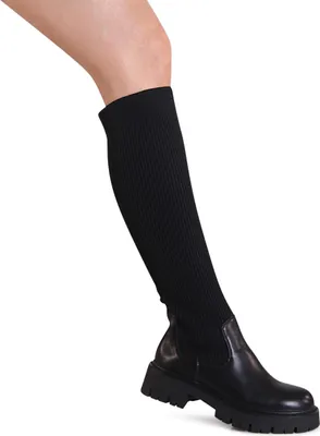 A person's leg wearing a black boot.