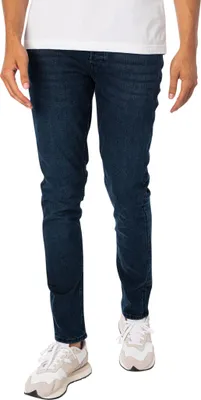 A person wearing jeans and sneakers, shown from the waist down.