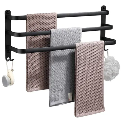 A black aluminum towel rack with three bars, holding three folded towels and a bath puff.