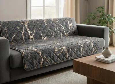 A quilted throw with a marble pattern is draped over a gray sofa in a living room setting.
