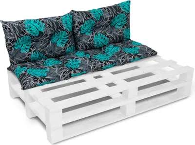 A white wooden pallet base with teal and black patterned cushions on top, forming a sofa or bench.