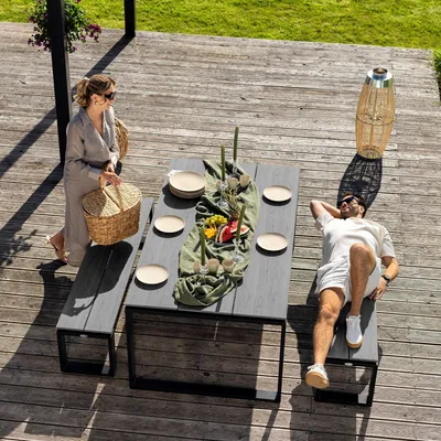 A couple enjoying a picnic on a wooden deck with a table and benches.