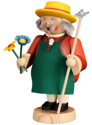Ein Räuchermann in einer grünen Schürze mit gelbem Sonnenhut hält zwei bunte Blumen in der einen Hand und eine Gartenhacke in der anderen während er eine Pfeife im Mund hat und freundlich aussieht