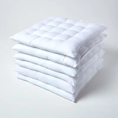 A stack of white seat cushions on a white background.