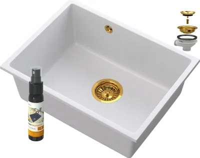 A white kitchen sink with gold fixtures and a spray bottle next to it.