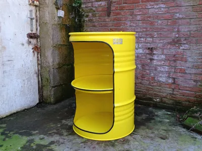 A yellow barrel shelf unit with two shelves is placed outdoors next to a brick wall and a white door.
