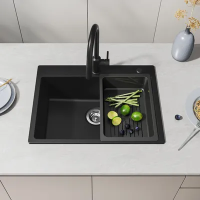 A black kitchen sink with a faucet and a tray of vegetables.
