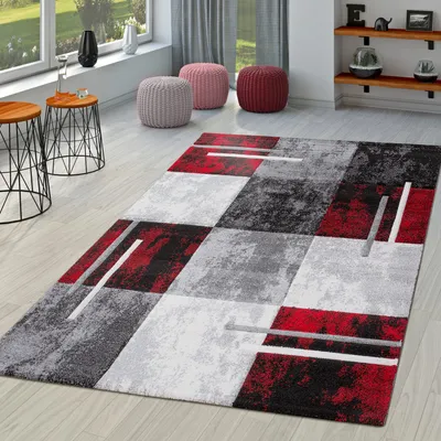 A modern living room scene with a geometric rug, side tables, and poufs.