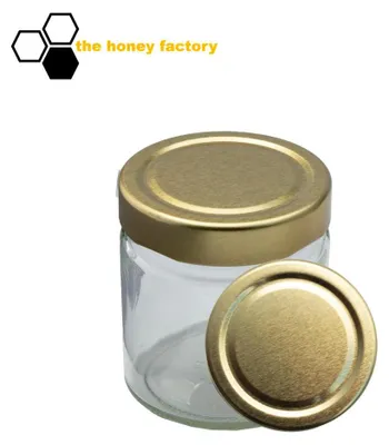 A clear studio shot of a glass jar with a gold lid, with a second lid placed in front of it. A logo and text are in the upper left corner.