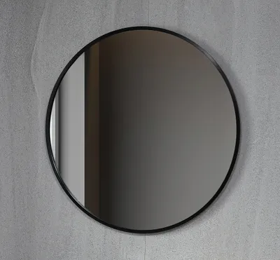 A round mirror with a black frame against a textured gray wall.