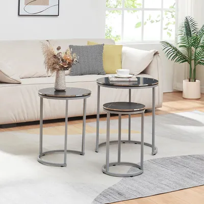 A living room scene with a sofa, coffee tables, and a plant.