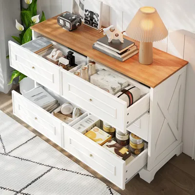A white and wood sideboard with open drawers filled with various items, placed in a room with a rug and plants.