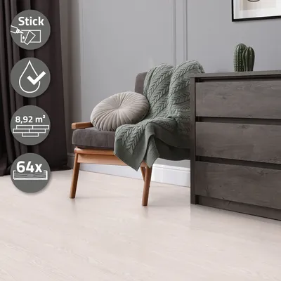 A chair with a blanket and pillow in a room with a dresser and a cactus.