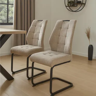 Two chairs in a dining room setting next to a table.