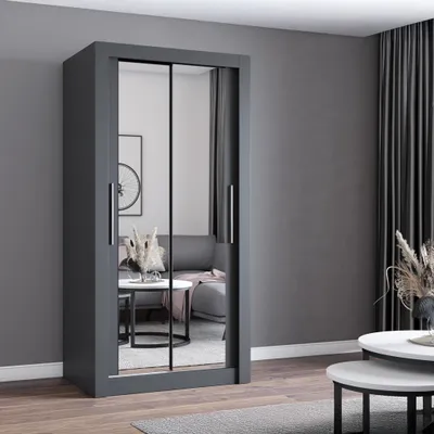 A modern gray wardrobe with mirrored doors is shown in a living room setting, reflecting a sofa and coffee table.