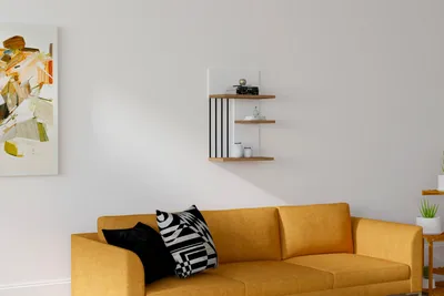 A living room scene with a yellow sofa, decorative pillows, and a wall-mounted shelf.