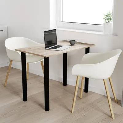 A small dining table with two chairs in a bright room, with a laptop and a mug on the table.