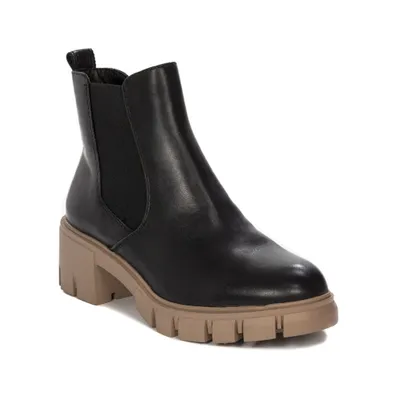 A black Chelsea boot with a tan lug sole and heel is shown against a white background.