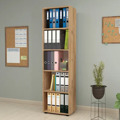 A tall, narrow bookshelf filled with binders and folders, placed in a room with a corkboard on the wall.