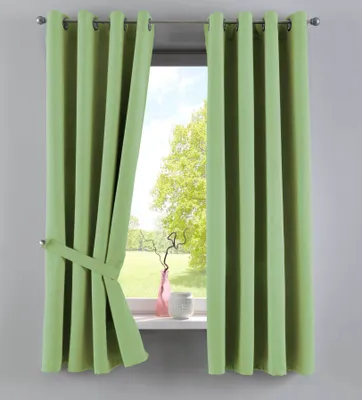 A pair of light green curtains are tied back with a fabric tie, revealing a window with a view of trees and a grassy field. A pink vase and a white ceramic pot sit on the windowsill.