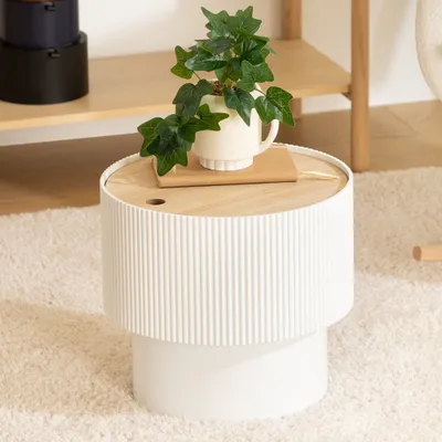A white side table with a wooden top and a potted plant on it, placed on a fluffy rug.
