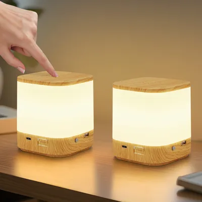 A hand is shown touching a wooden-cased LED night light, with another identical light visible in the background.
