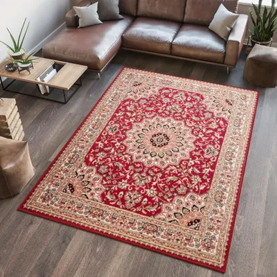 A red oriental rug is placed on a dark wooden floor in a living room setting with a brown leather sectional sofa and a wooden coffee table.