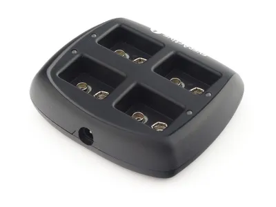 A black battery charger with four slots for batteries.