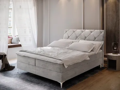 A bedroom scene featuring a large upholstered bed with a tufted headboard, set against a wall with curtains and a window seat.