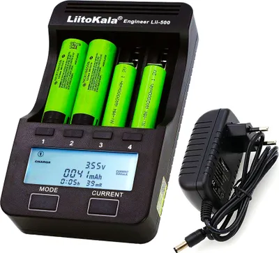 A black battery charger with four green batteries inserted, and a black power adapter next to it.
