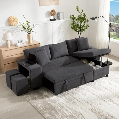 A gray sectional sofa with storage and USB ports is set up in a living room with a wooden dresser, a plant, and a floor lamp.