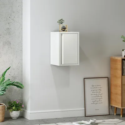 A white wall-mounted cabinet with a mirrored door is shown in a room setting, with plants and a framed picture visible.