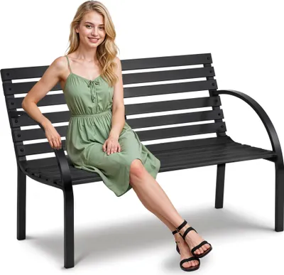 A woman is sitting on a black garden bench.
