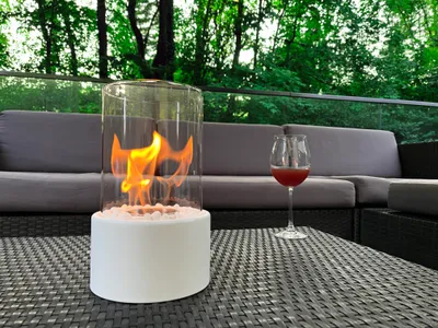 Produktbild von ANDEKO Bioethanol Tischkamin – Tischfeuer Indoor & Outdoor – 4h Brenndauer - Rauchfrei & Geruchlos  –  Inkl. Sicherheitsglas & Deko-Steine Ø16cm H31cm