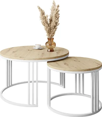 Two round coffee tables of different sizes, one nested under the other, with a vase of dried flowers and a cup of coffee on the larger table.